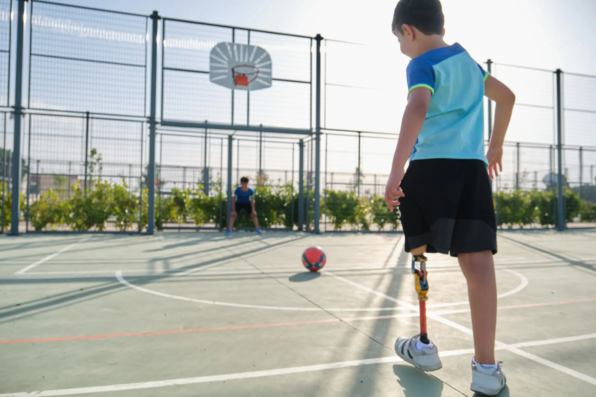 A child preparing to kick a soccer ball on an outdoor court.