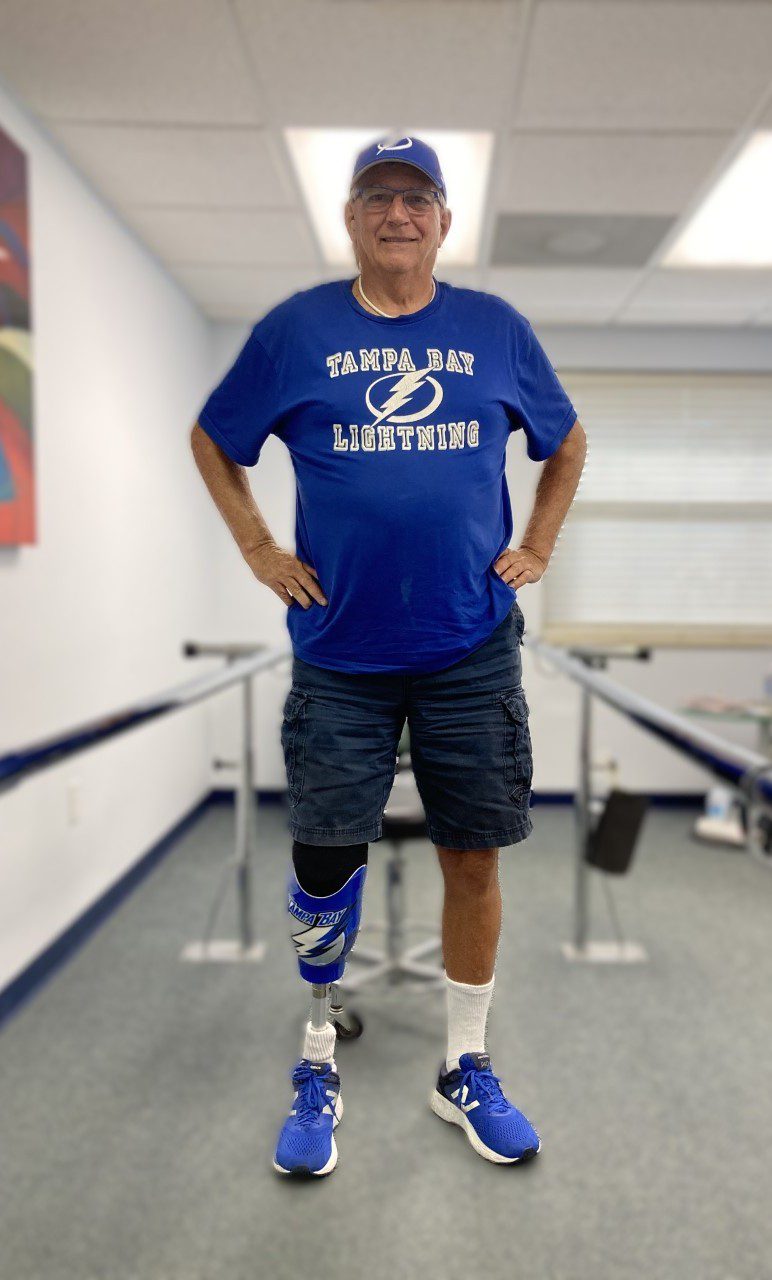 A person with a prosthetic leg wearing a blue shirt and shorts.
